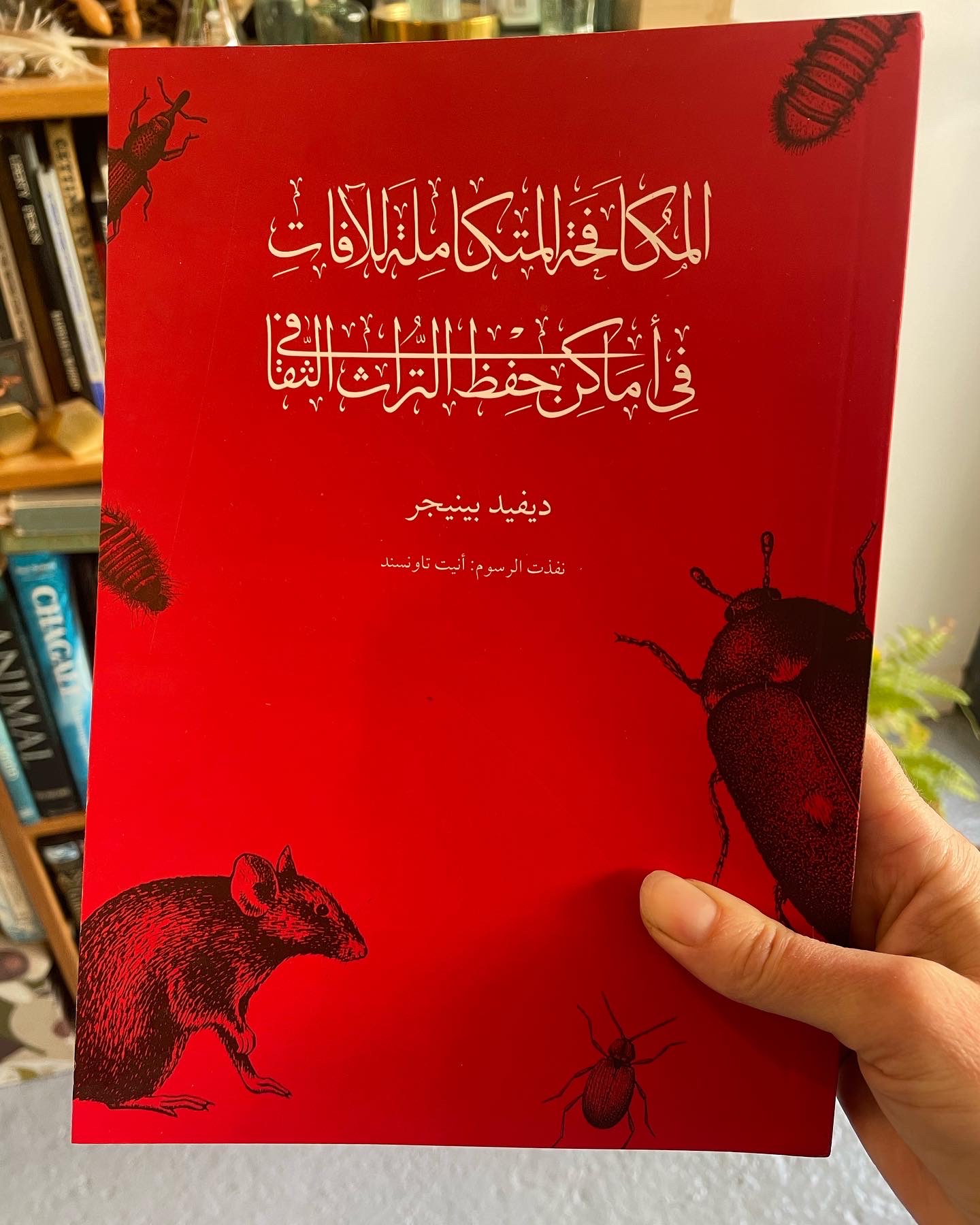 Front cover of the Arabic edition of IPM in Cultural Heritage book with white text on a red background and black insect illustrations